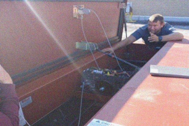 A man kneels against an open smoke hatch.