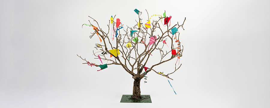 a photo of an artist's miniature model of kites strewn throughout a tree with no leaves