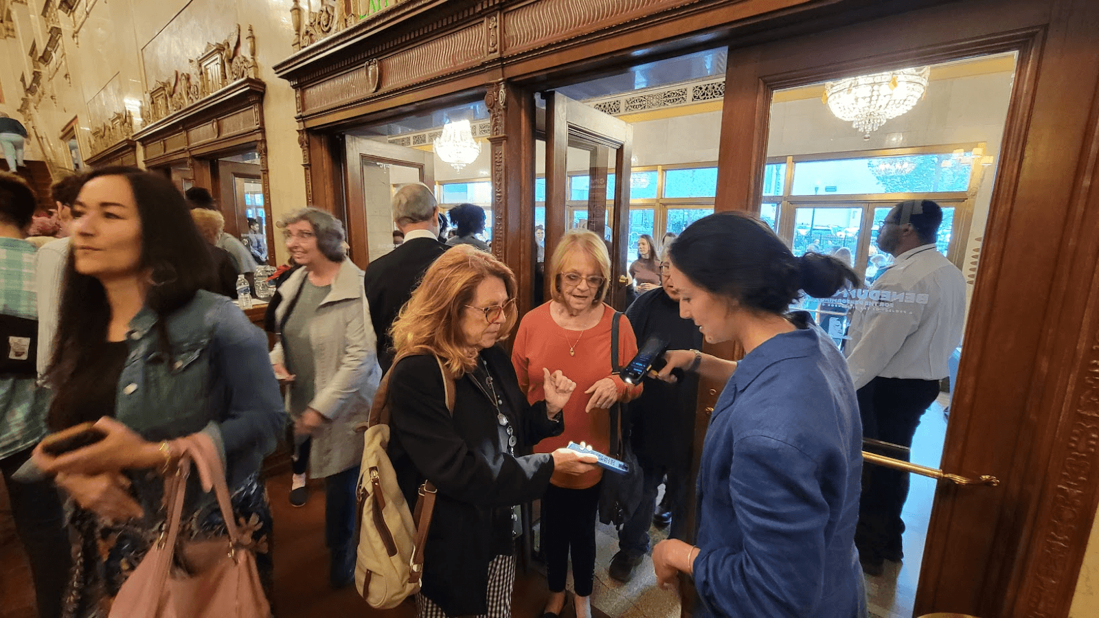 A woman in a blue jacket scans tickets as a group of patrons file in through the Benedum Center doors.