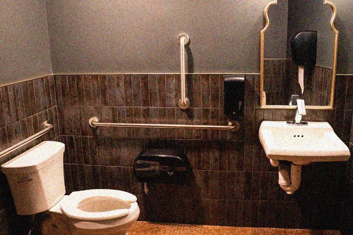 A bathroom with bars on the wall around the toilet to hold onto.