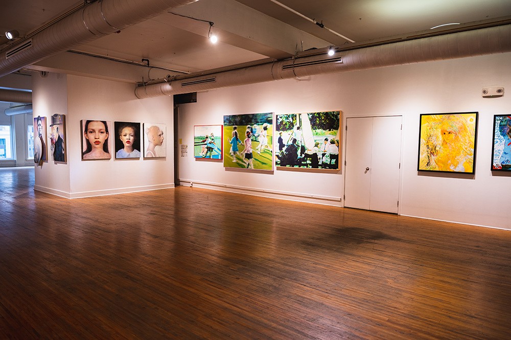 a large gallery space with numerous realist paintings hung on the walls