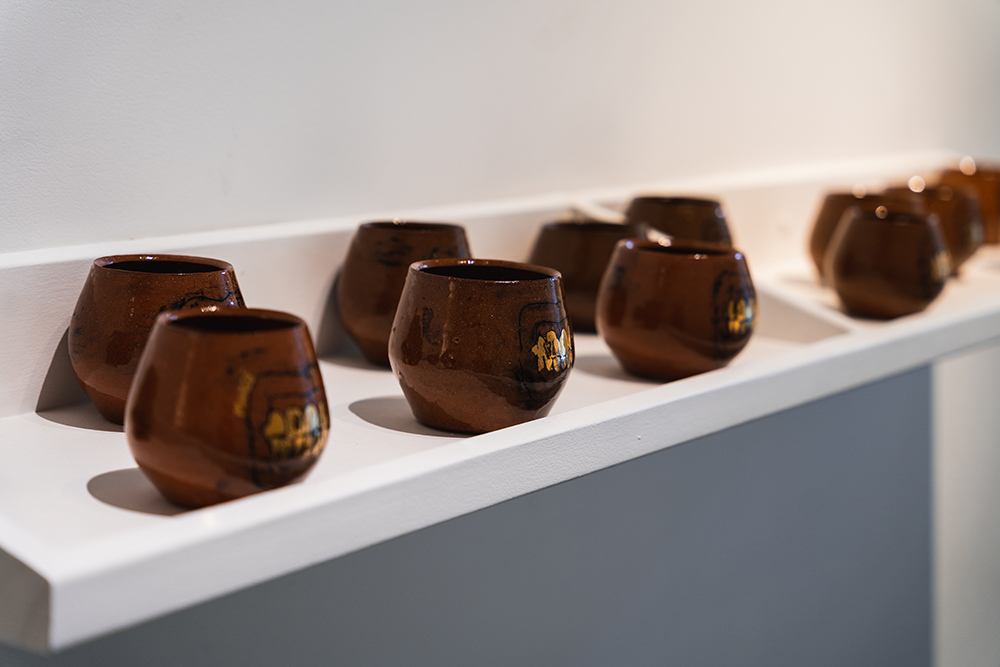 a collection of small brown ceramic pots sitting on a shelf