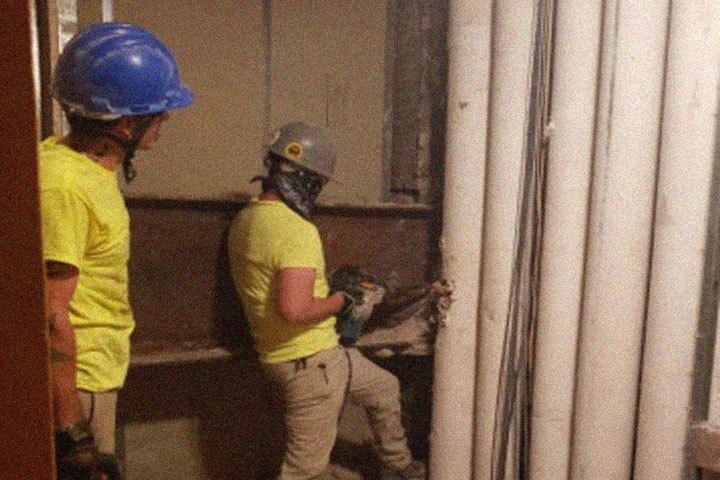 Construction workers cut through piping to make space for elevator expansion.