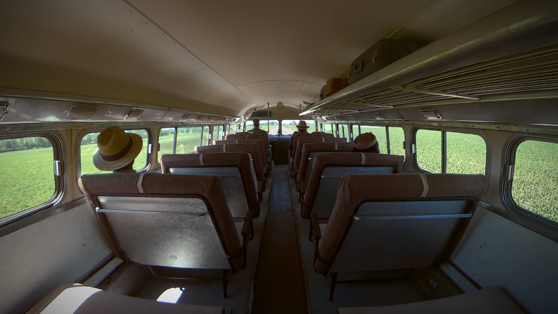 a fisheye point of view image from the perspective of a person sitting in a vintage bus, driving down a dirt road