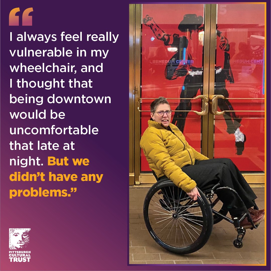 Tess poses in her wheelchair in front of the Benedum Center doors, which are wrapped in the red and black MJ the Musical logo.