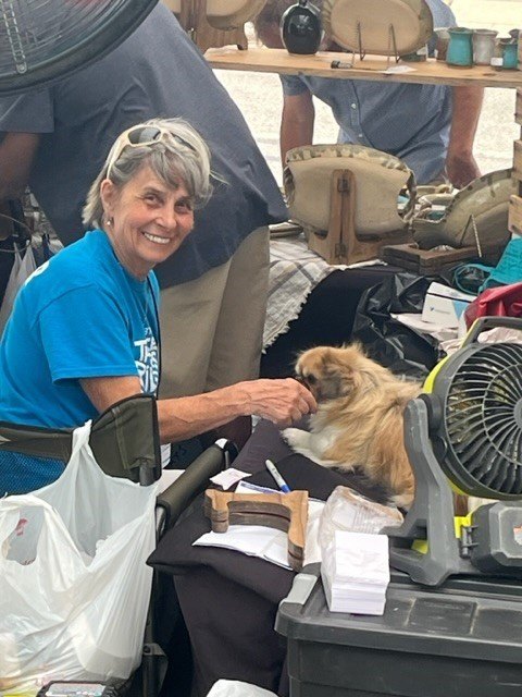 volunteer in blue TRAF volunteer smiles at the camera and holds out her hand to a dog