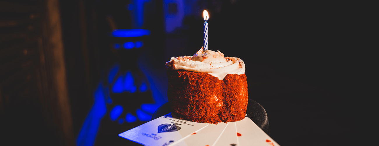 cupcake with a birthday candle resting on top of playing cards