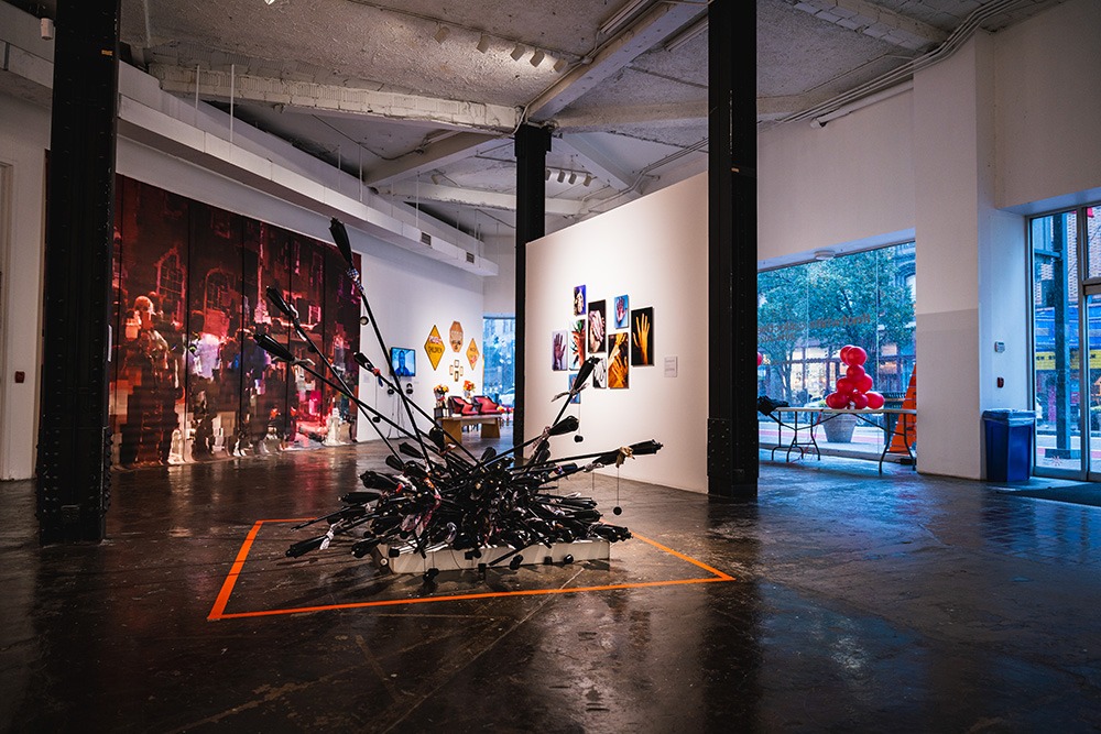 a sculpture made out of tiki torches sits on the floor. a maroon mural is hung on the wall behind it.