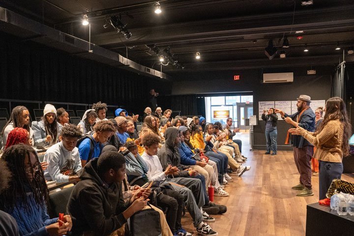 An instructor stands in front of a seated group of students.