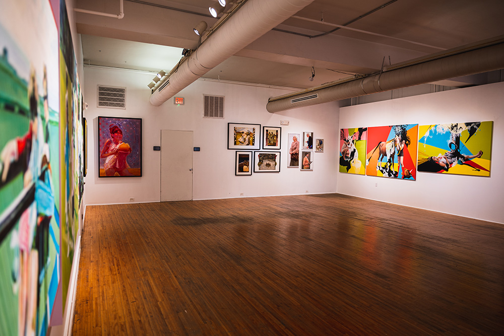 a large gallery space with colorful paintings hung on three walls