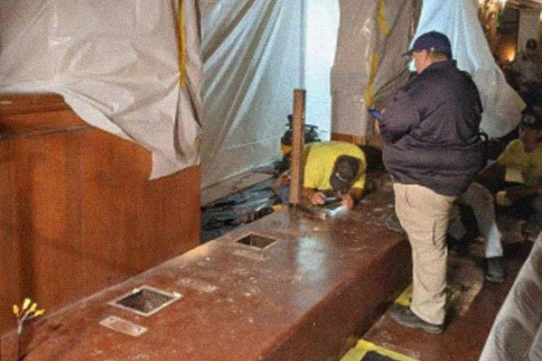 Construction workers work on stripping down the stair riser for the new seating.