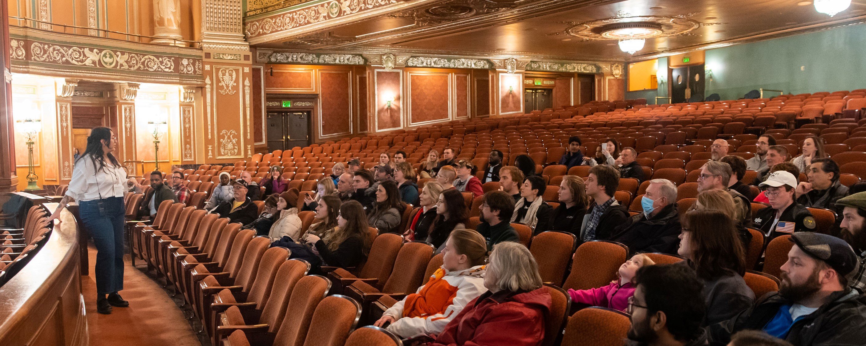 a group of people sit in Benedum Center seats, facing a tour guide