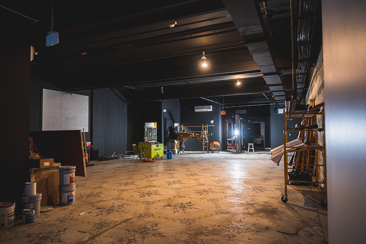 a large space with black walls that is mid construction. tools lay and materials clutter the space.