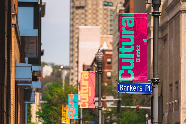 a city block on a sunny day. colorful banners that say 'cultural district' hang from street poles