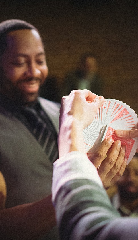 an audience member chooses a card out of a deck being held by a magician