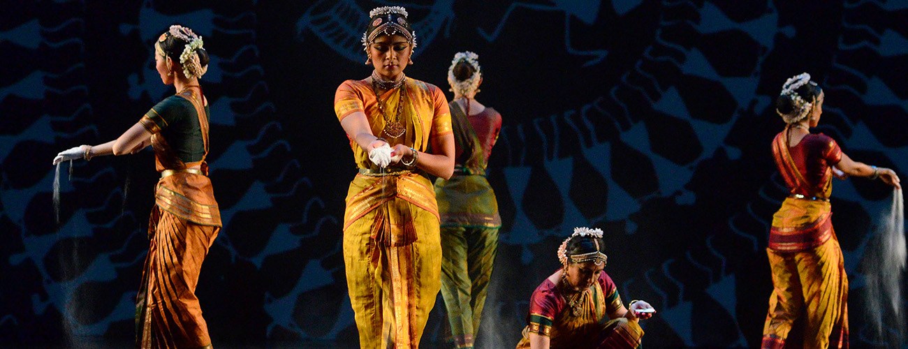 a group of indian dancers in colorful earth toned outfits all stand on stage