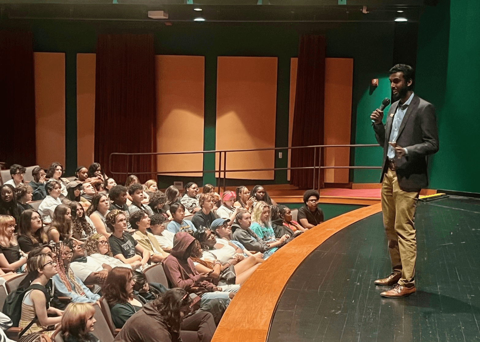 Vinay Thomas speaks from the stage to a group of students