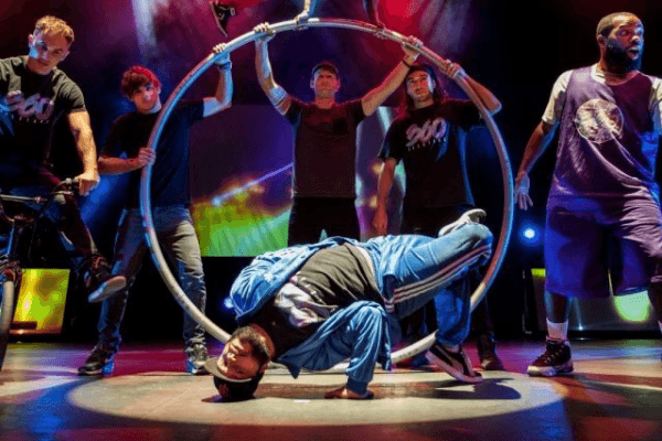 a man breakdances in the center while other men around him perform other tricks
