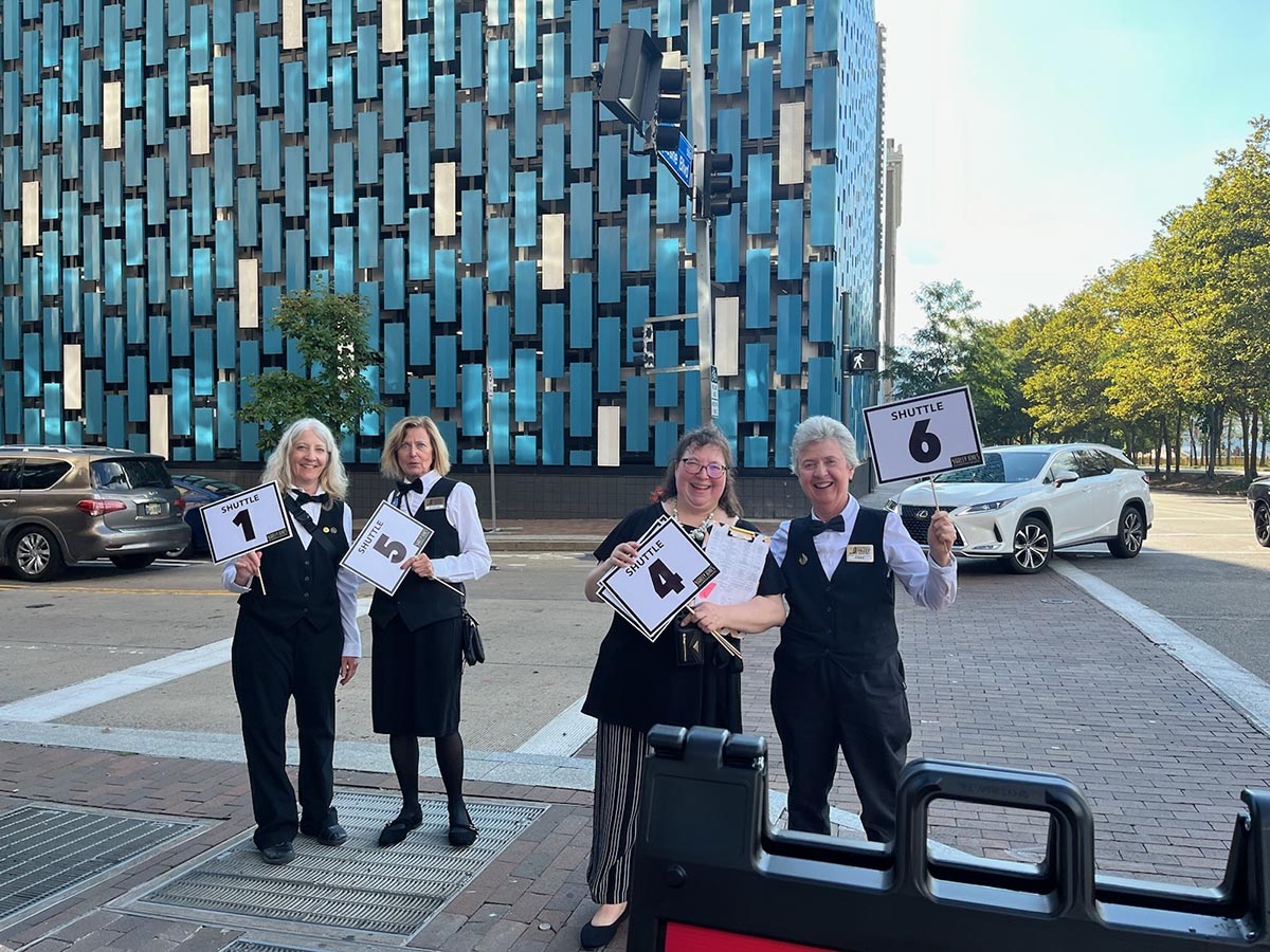 Four volunteers outside holding signs that say 'shuttle'