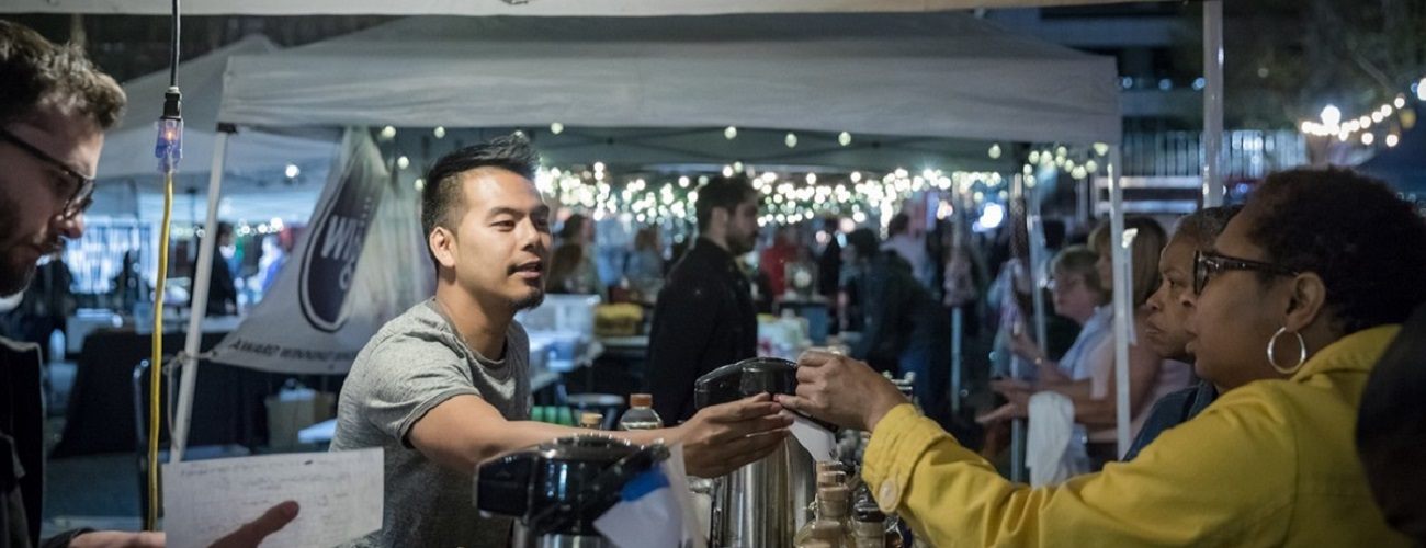 person making a purchase at an outdoor booth at night