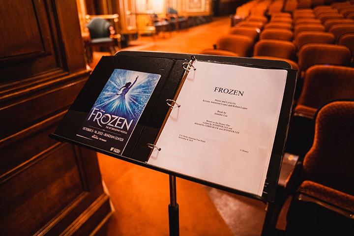 a music stand with a frozen playbook and printed script sitting on it